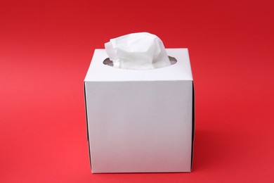 Photo of Box with paper handkerchiefs on red background