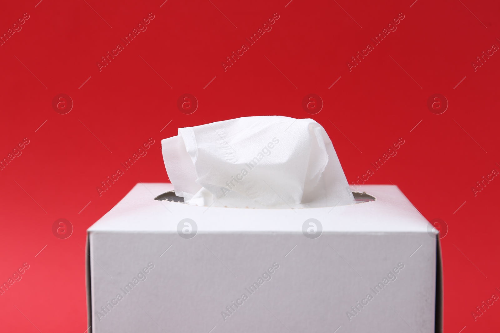 Box with paper handkerchiefs on red background, closeup Photo of Box with paper handkerchiefs on red background, closeup