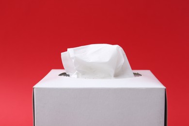 Photo of Box with paper handkerchiefs on red background, closeup