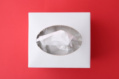 Photo of Box with paper handkerchiefs on red background, top view