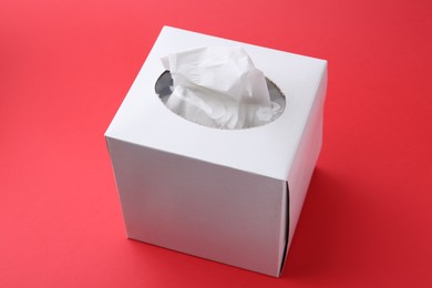 Photo of Box with paper handkerchiefs on red background, closeup