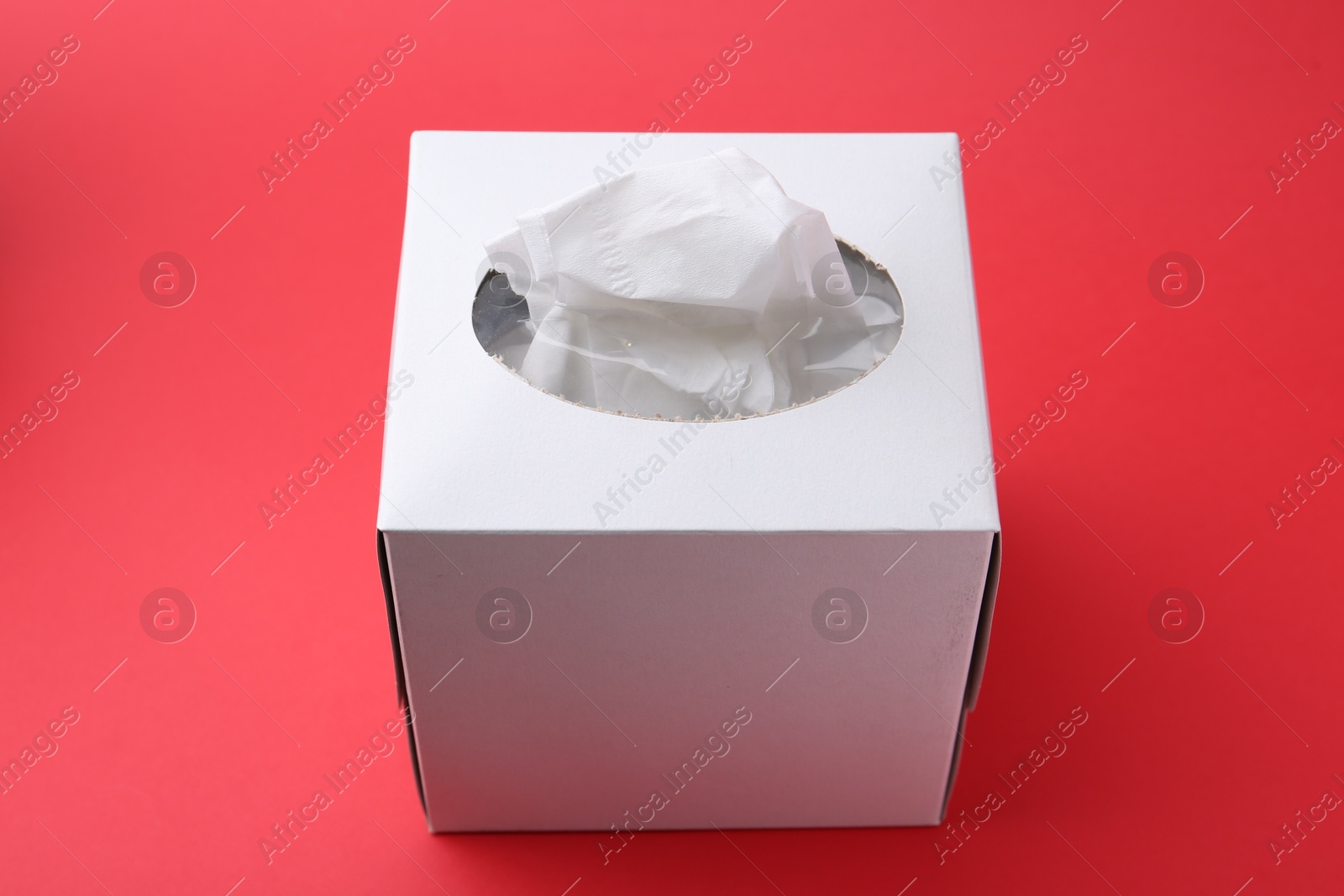 Box with paper handkerchiefs on red background, closeup Photo of Box with paper handkerchiefs on red background, closeup