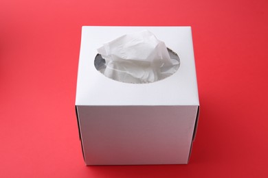 Photo of Box with paper handkerchiefs on red background, closeup