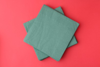 Photo of Stack of green handkerchiefs on red background, top view