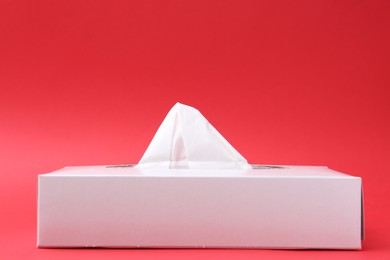 Photo of Box with paper handkerchiefs on red background. Space for text