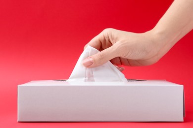 Photo of Woman taking handkerchief out of box on red background, closeup