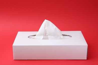 Photo of Box with paper handkerchiefs on red background. Space for text