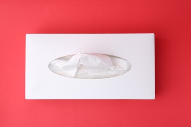 Photo of Box with paper handkerchiefs on red background, top view