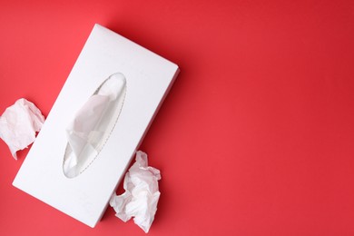 Photo of Box with paper handkerchiefs on red background, top view. Space for text