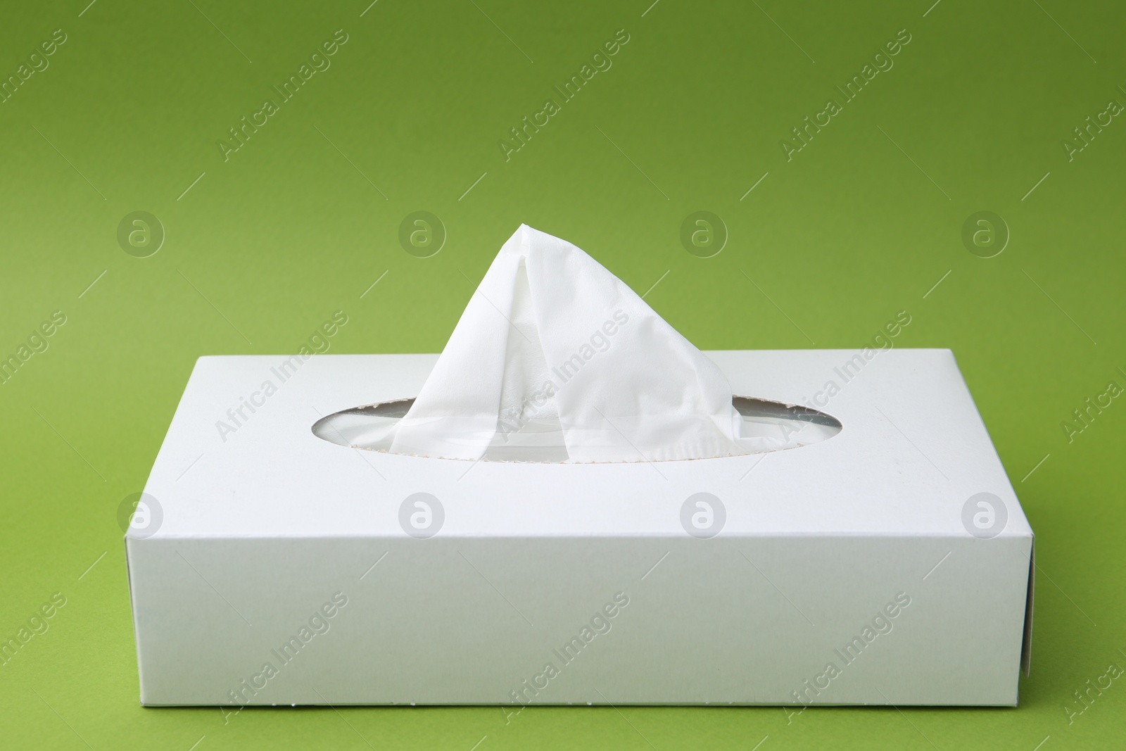 Box with paper handkerchiefs on green background Photo of Box with paper handkerchiefs on green background