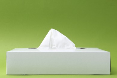 Photo of Box with paper handkerchiefs on green background. Space for text