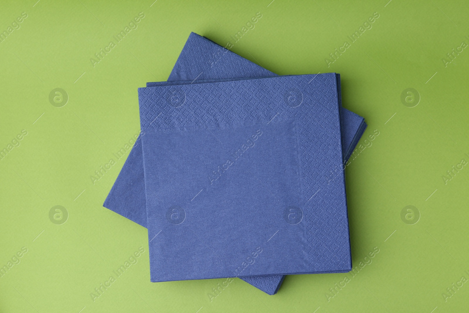 Stack of blue handkerchiefs on green background, top view Photo of Stack of blue handkerchiefs on green background, top view