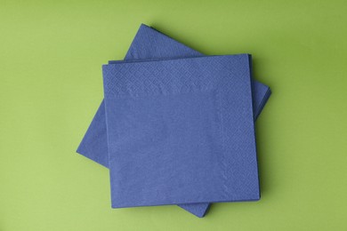 Photo of Stack of blue handkerchiefs on green background, top view