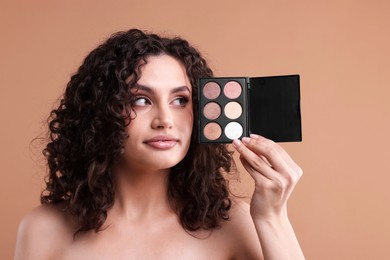 Photo of Woman with eyeshadow palette on beige background