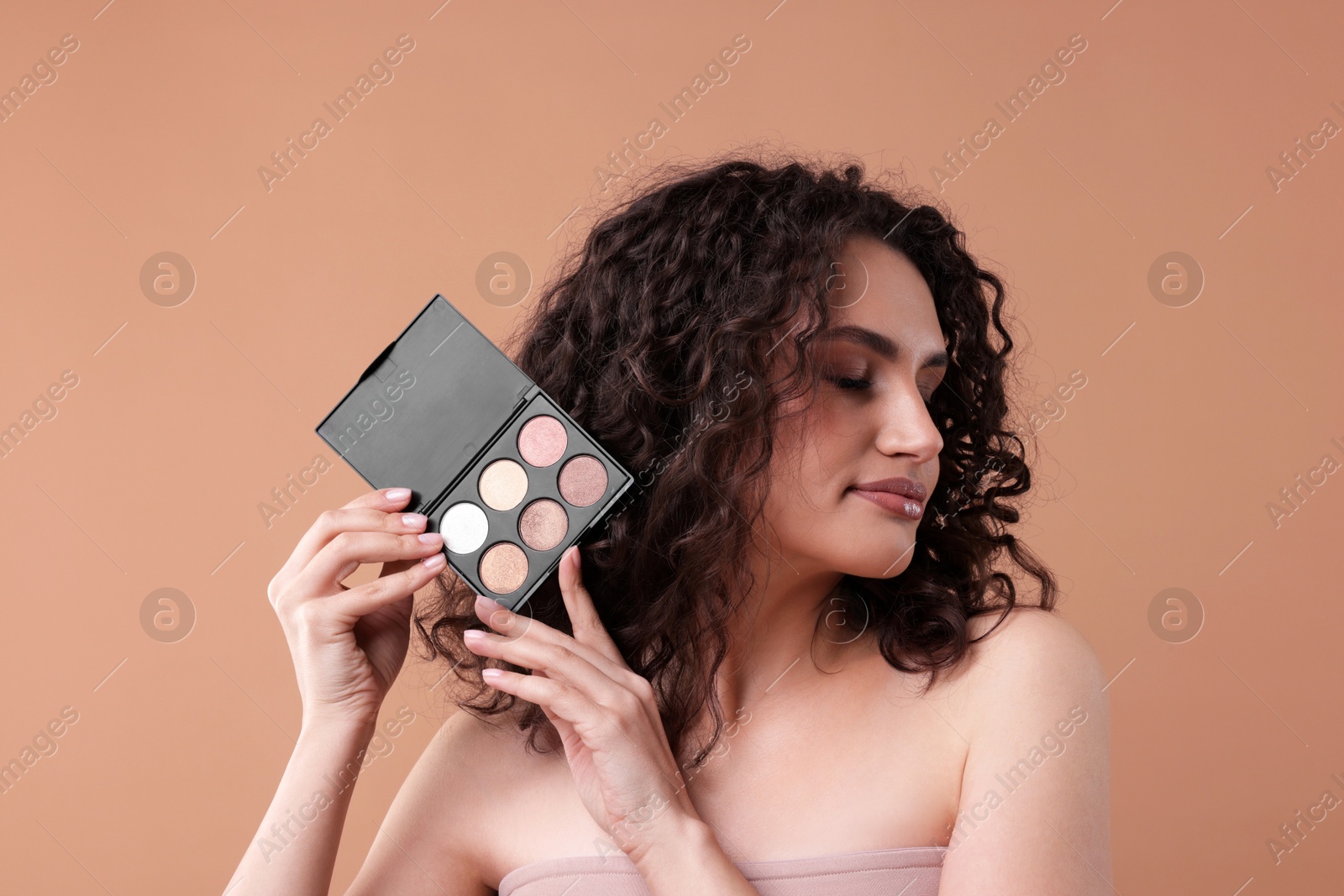Woman with eyeshadow palette on beige background Photo of Woman with eyeshadow palette on beige background