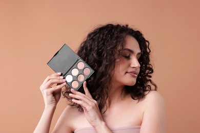 Photo of Woman with eyeshadow palette on beige background