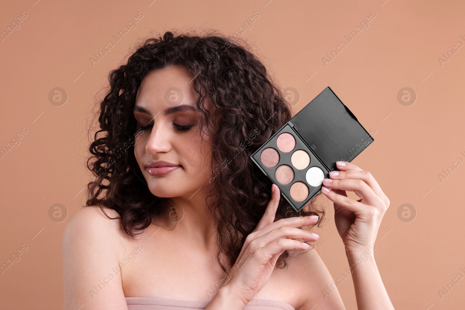 Woman with eyeshadow palette on beige background Photo of Woman with eyeshadow palette on beige background