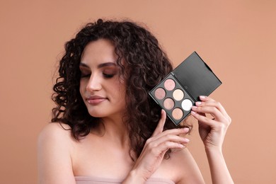 Photo of Woman with eyeshadow palette on beige background