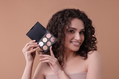 Photo of Smiling woman with eyeshadow palette on beige background