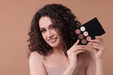 Photo of Smiling woman with eyeshadow palette on beige background
