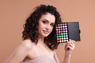 Photo of Smiling woman with eyeshadow palette on beige background