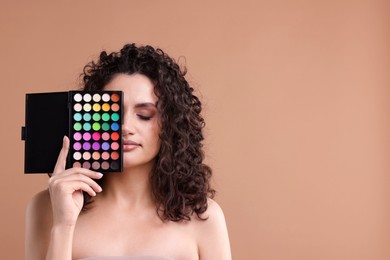 Photo of Woman covering eye with eyeshadow palette on beige background. Space for text