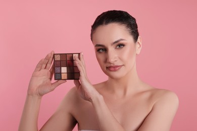 Photo of Woman with eyeshadow palette on pink background