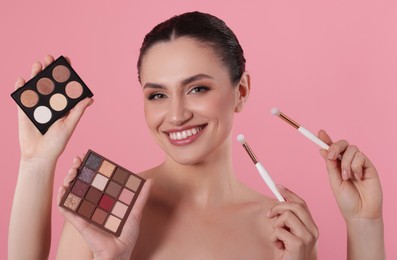 Photo of Makeup artist with eyeshadow palettes, brushes and smiling woman on pink background, closeup