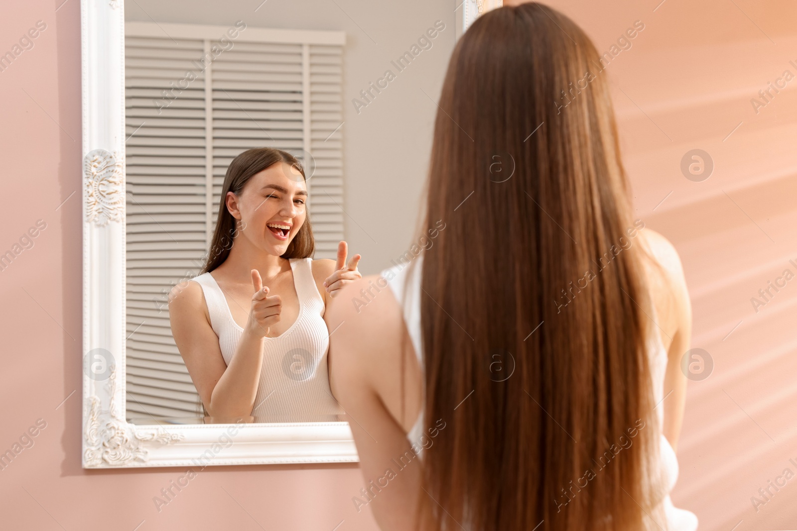 Beautiful woman looking at herself in mirror indoors Photo of Beautiful woman looking at herself in mirror indoors