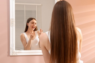 Photo of Beautiful woman looking at herself in mirror indoors