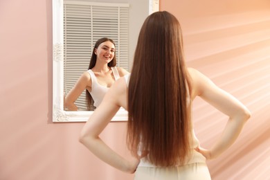 Photo of Beautiful woman looking at herself in mirror indoors