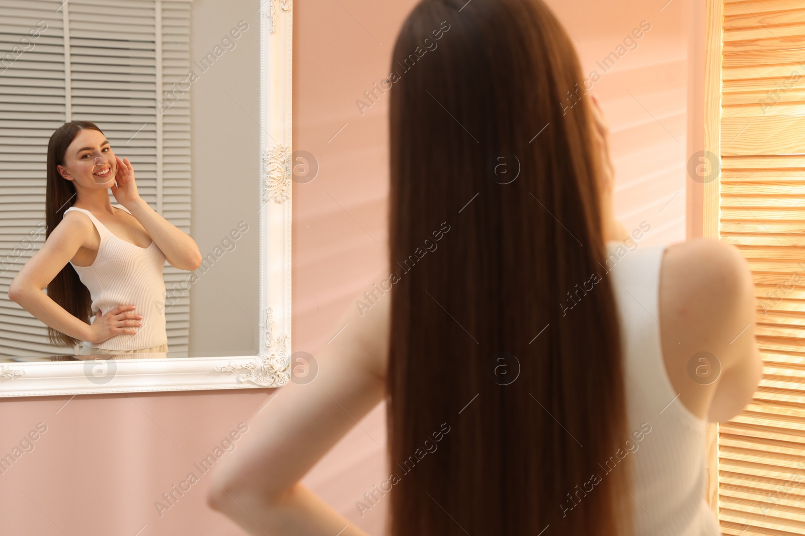 Beautiful woman looking at herself in mirror indoors Photo of Beautiful woman looking at herself in mirror indoors