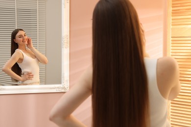 Photo of Beautiful woman looking at herself in mirror indoors