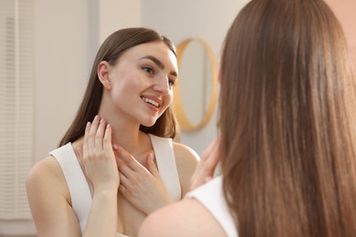 Photo of Beautiful woman looking at herself in mirror indoors