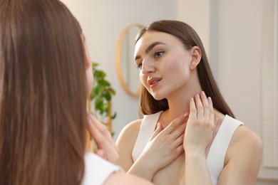 Photo of Beautiful woman looking at herself in mirror indoors