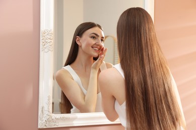 Photo of Beautiful woman looking at herself in mirror indoors