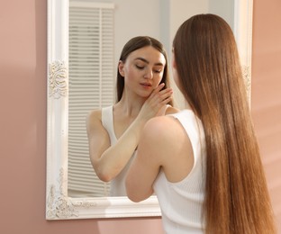 Photo of Beautiful young woman posing near mirror indoors