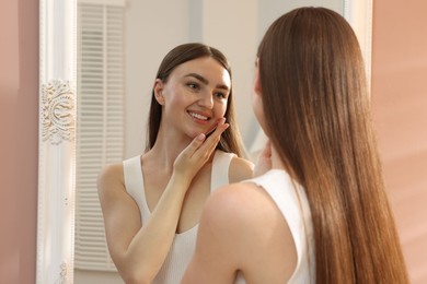 Photo of Beautiful woman looking at herself in mirror indoors