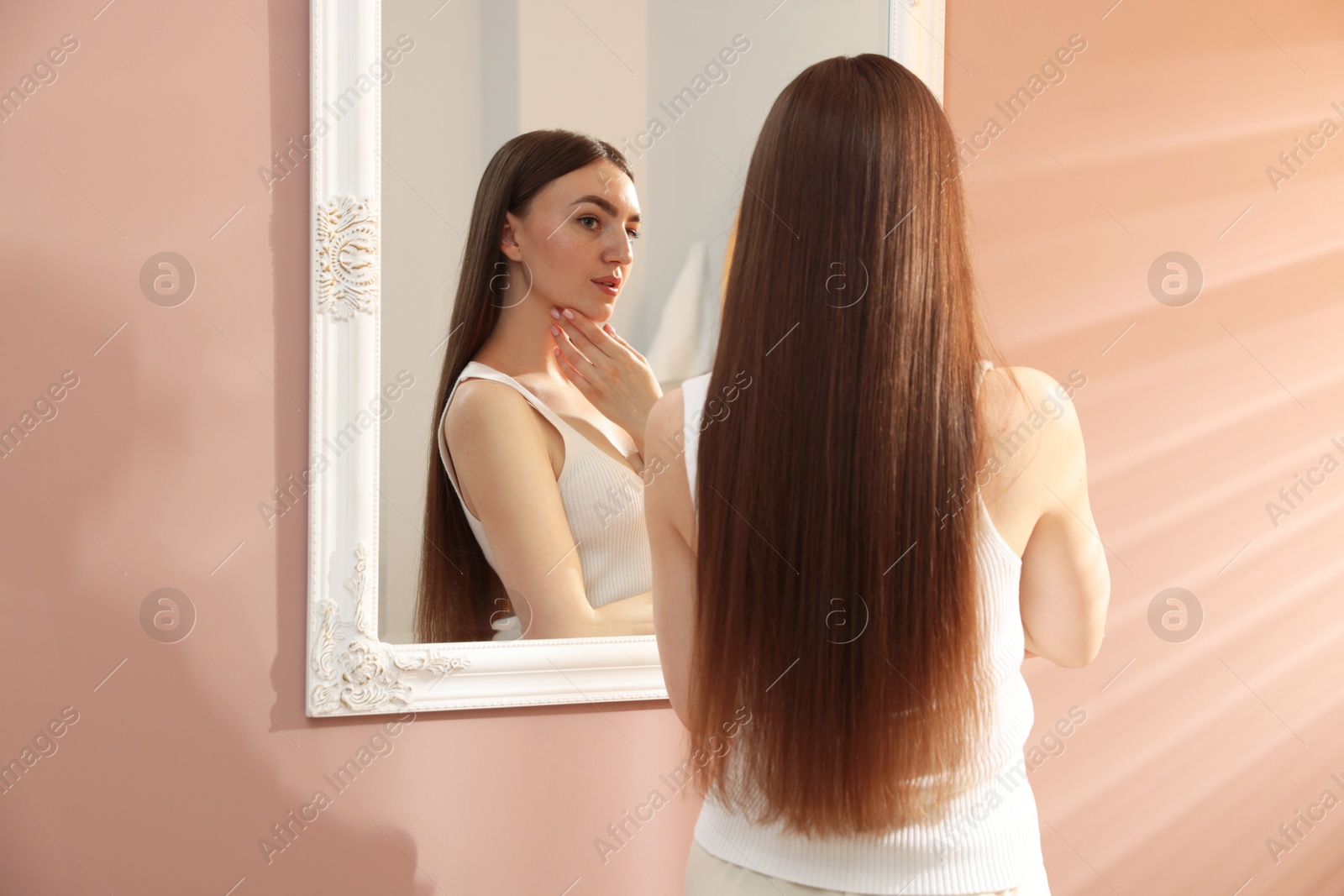 Beautiful woman looking at herself in mirror indoors Photo of Beautiful woman looking at herself in mirror indoors