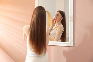 Photo of Beautiful woman looking at herself in mirror indoors