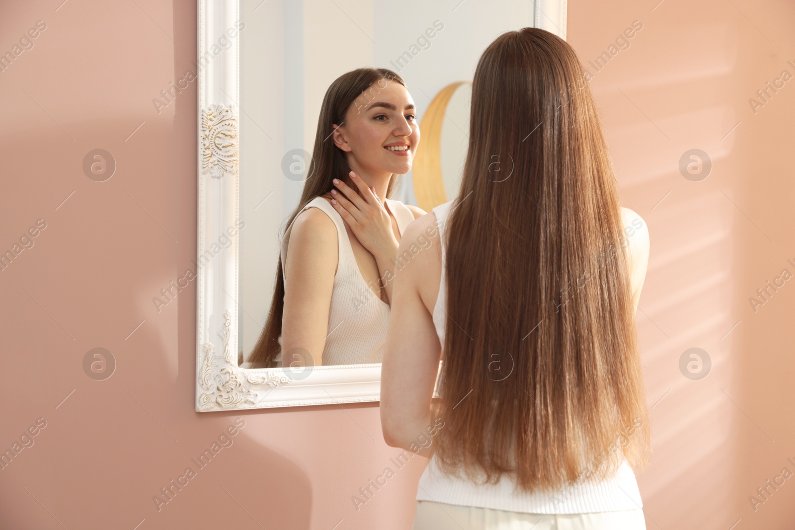 Beautiful woman looking at herself in mirror indoors Photo of Beautiful woman looking at herself in mirror indoors