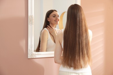 Photo of Beautiful woman looking at herself in mirror indoors