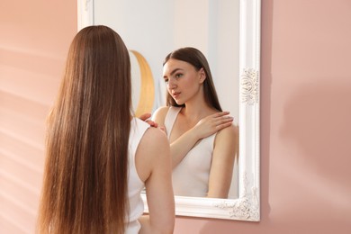 Photo of Beautiful woman looking at herself in mirror indoors