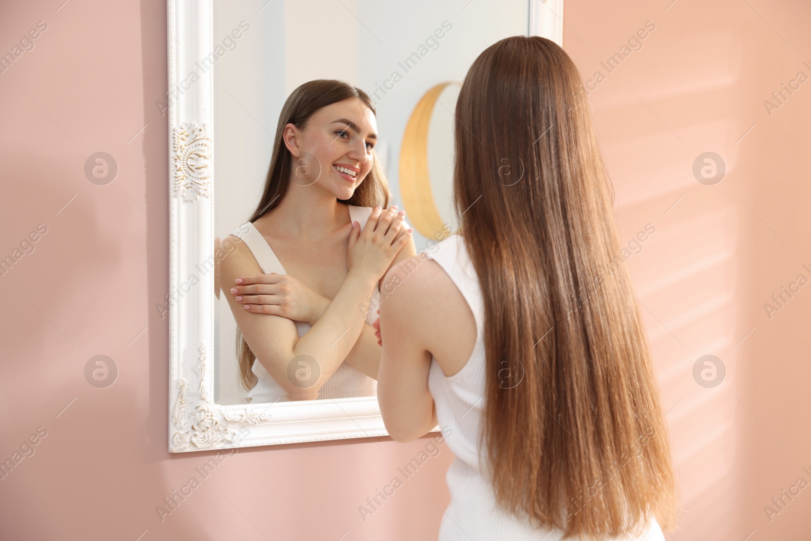 Beautiful woman looking at herself in mirror indoors Photo of Beautiful woman looking at herself in mirror indoors