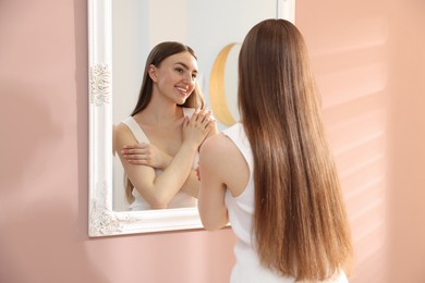 Photo of Beautiful woman looking at herself in mirror indoors