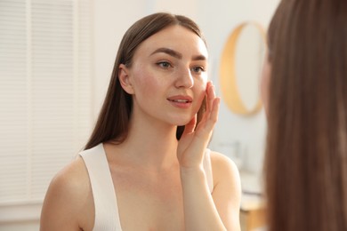 Photo of Beautiful woman looking at herself in mirror indoors