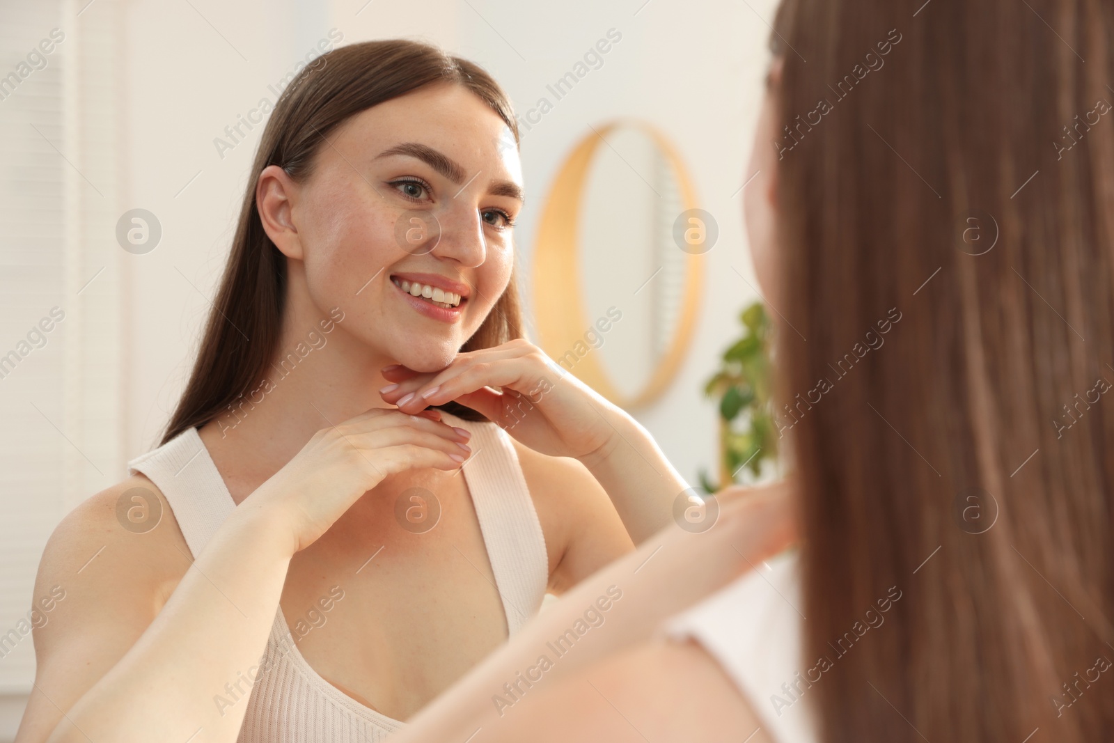 Beautiful woman looking at herself in mirror indoors Photo of Beautiful woman looking at herself in mirror indoors
