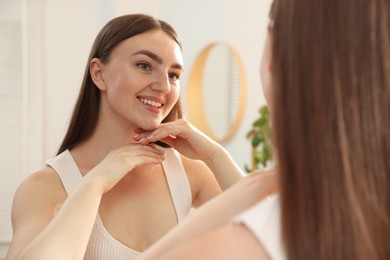 Photo of Beautiful woman looking at herself in mirror indoors