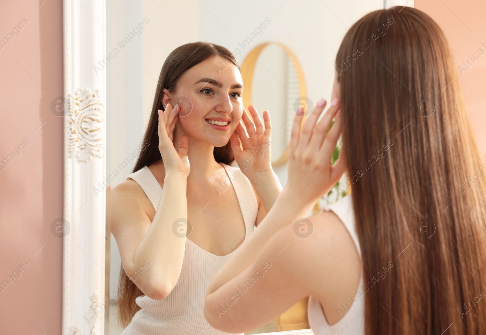 Beautiful woman looking at herself in mirror indoors Photo of Beautiful woman looking at herself in mirror indoors