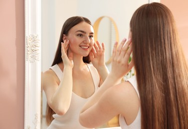 Photo of Beautiful woman looking at herself in mirror indoors